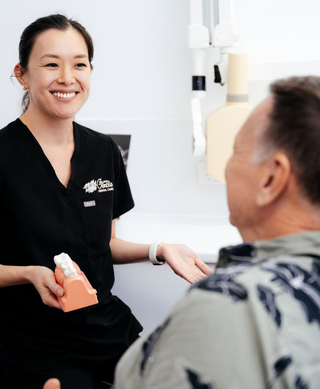 Dentist consulting patient with teeth model.