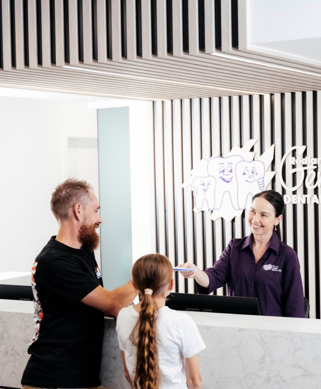 Receptionist greeting family at dental clinic desktop