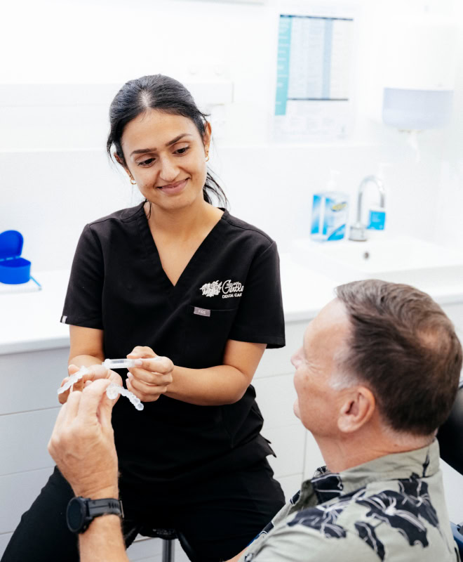 Dentist explaining dental model to patient in clinic.
