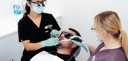 Dentists performing dental checkup on patient.
