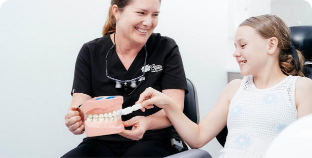 Dentist teaching girl dental hygiene with model.