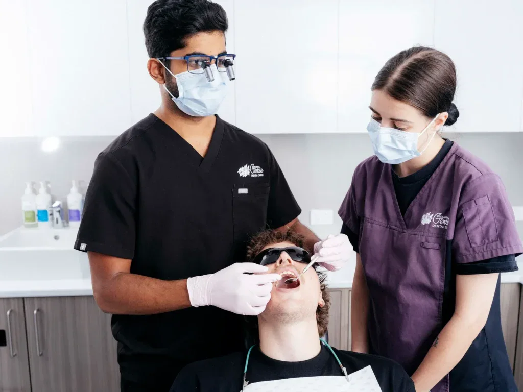 Dentist and assistant examining patient's teeth.