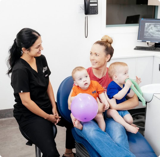 Dentist with mother and twins in clinic.