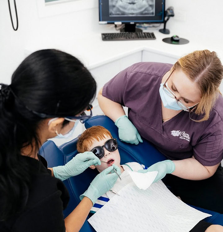 Child receiving dental check-up with two dentists.