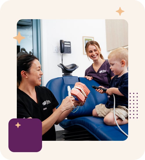 Dentist teaching child oral hygiene with teeth model.