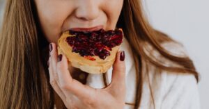 A person eating a slice of bread with peanut butter and jam—can you eat with Invisalign?.