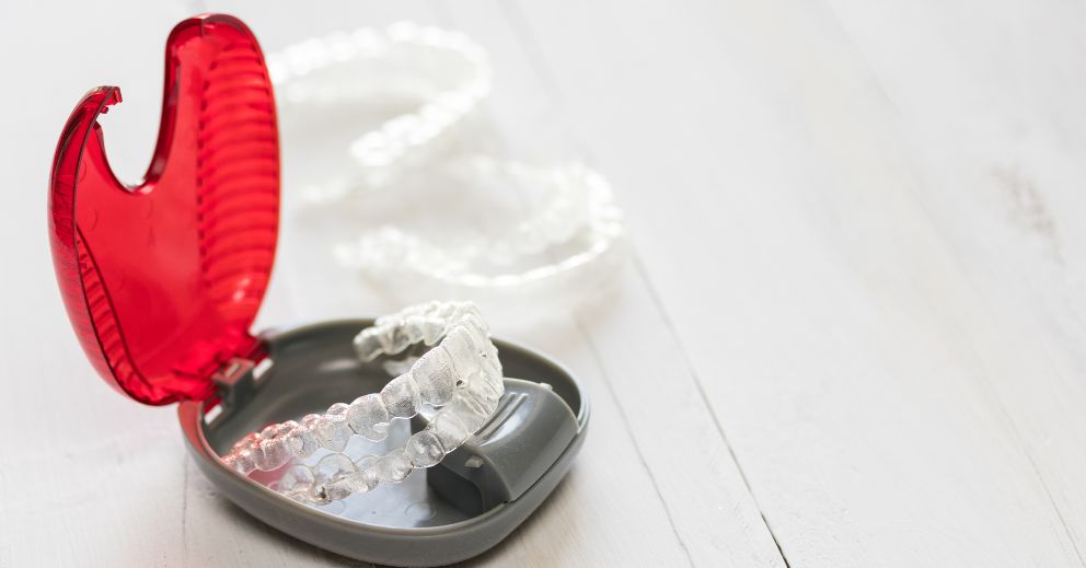 Clear dental aligners in a grey case—learn how to clean Invisalign retainers for best care.