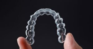 Clear dental aligner, highlighting the difference between Invisalign vs Braces.