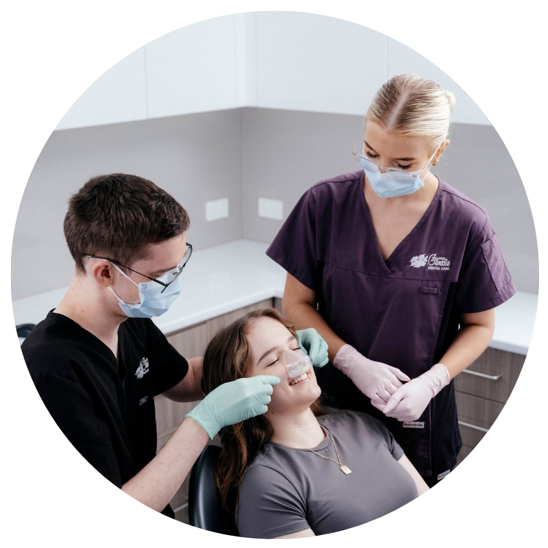 Dentists examining patient's teeth in clinic.