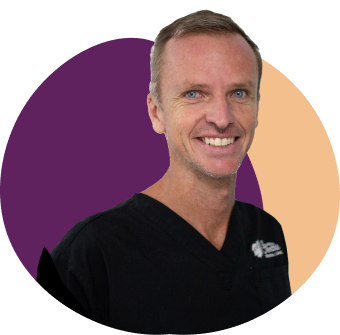Smiling person in black shirt with colourful background.