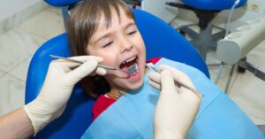Child in dental chair getting a check-up; how often should children visit the dentist for oral health?.