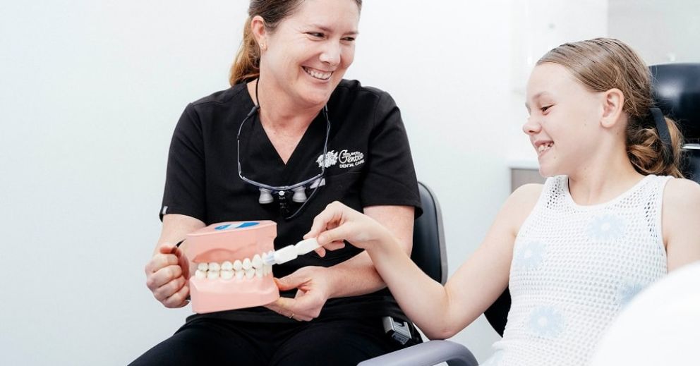 Dentist teaching a child how to brush their teeth during a first dental visit
